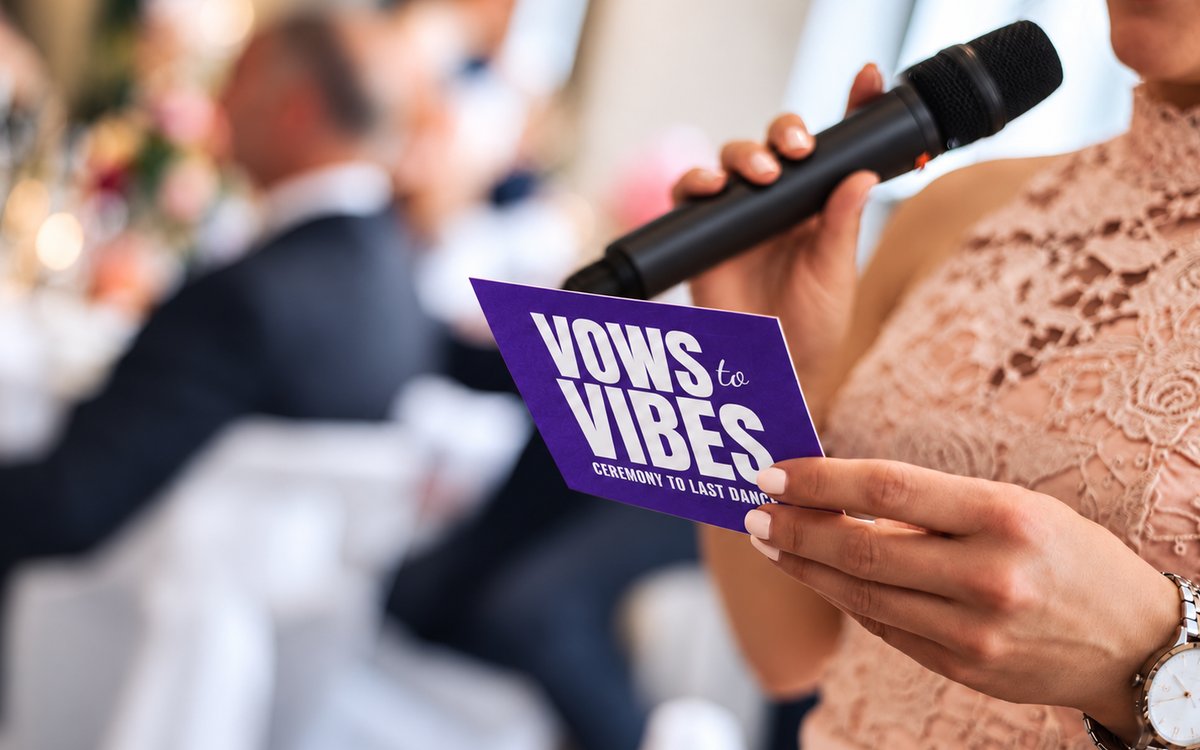A bridesmaid reading out a Vows to Vibes advice card into a microphone